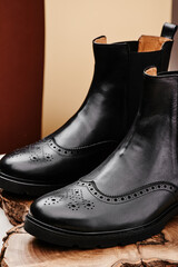 Black leather chelsea boots made of genuine leather in classic style on a wooden cut. Close-up. High quality photo