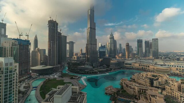 Skyscrapers rising above Dubai downtown timelapse, mall and fountain surrounded by modern buildings aerial top view