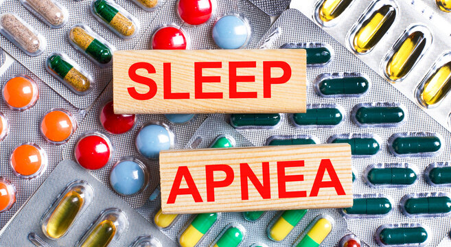 Against the background of multi-colored plates, wooden blocks with the text SLEEP APNEA. Medical concept.