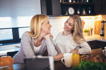 Happy mother and daughter making breakfast at home kitchen and spend time together