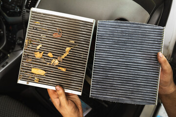 An auto mechanic shows a close-up of an old and new cabin air filter for comparison