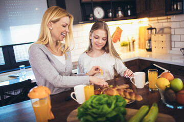 Happy mother and daughter making breakfast at home kitchen and spend time together