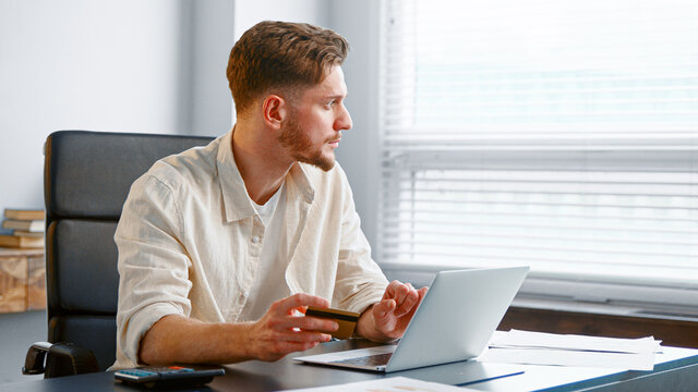 Young man with beard pays online holding credit card