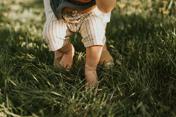 Close up of kids legs on a grass. Baby feeling grass for the first time. Family concept