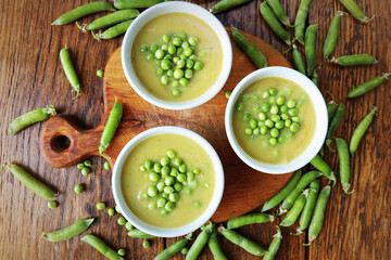 Fresh green pea soup with pea seeds and pea pods around . Selective Focus, Focus on the pea in the middle of the soup. Top view
