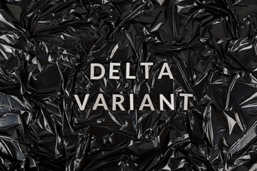words delta variant laid with silver metal letters on crumpled black plastic bag background