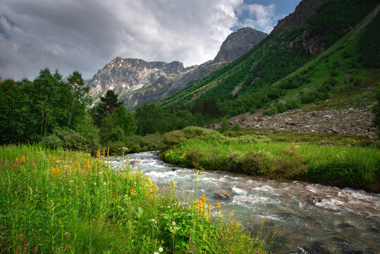 A beautiful alpine gorge of the Ullu-Murudzhu River with green meadows and mountain peaks in the Karachay-Cherkess Republic