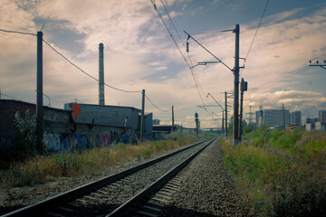 neglected railway, rails to nowhere, grass and graffiti, factory pipe in the background