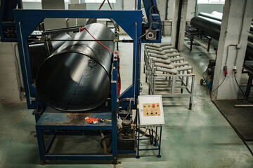 a worker of a pipe-rolling plant. conveyor line of the ferrous metallurgy enterprise. a worker in a uniform is engaged in metal welding