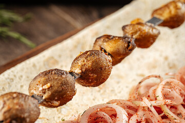 Caucasian grilled potato shashlyq skewers on a wooden background