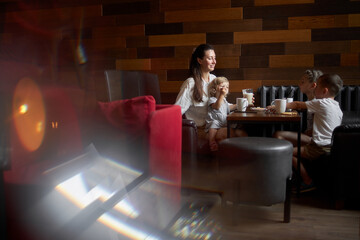 Mother with children drinking hot chocolate and latte at a local coffee shop. They are smiling and having fun. Motherhood concept