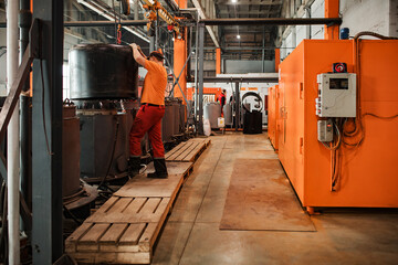 a worker of a pipe-rolling plant. conveyor line of the ferrous metallurgy enterprise. a worker in a uniform is engaged in metal welding