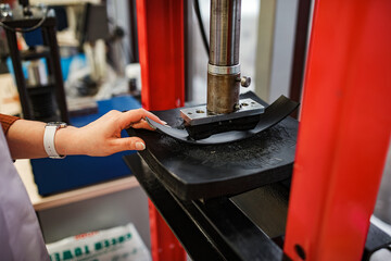 a worker with an industrial press. hold the workpiece in your hands for the part to work under high pressure. automated production machine operator