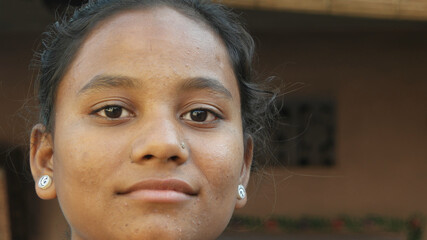Closeup of a young Indian girl's face with a nose piercing in front of a blurry background