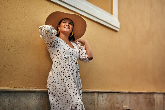 mujer en el centro de sincelejo acomodando sombrero sonriendo mirando hacia arriba 
