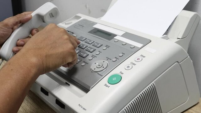 hand man is using a fax machine in the office, equipment for data transmission.