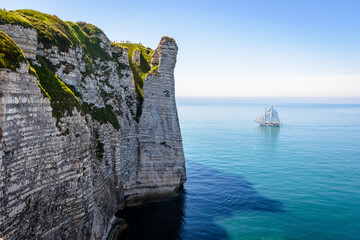 A sailing ship is cruising off the Aval cliff in Etretat, France