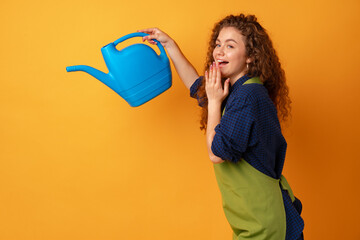 Portrait of a beautiful woman gardener with watering can against yellow background © fotofabrika