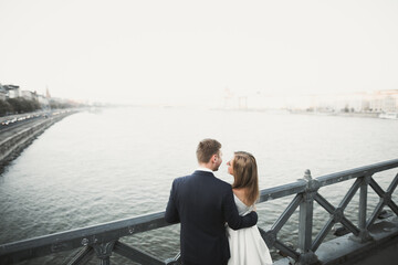 Young beautiful stylish pair of newlyweds on a bridge