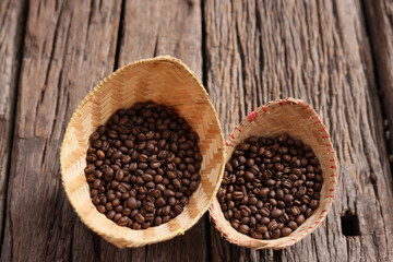 Fototapeta na wymiar hand hold Coffee Beans Peaberry small size picking . a cup and log wooden background. Selective focus on foreground with copy space.