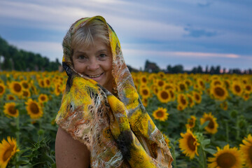 elderly beautiful woman in a field of sunflowers laughs and enjoys life