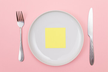 Colored Sticky Note or Memo Paper on White Ceramic Plate Lying On Pink Background - Top View, Flat Lay