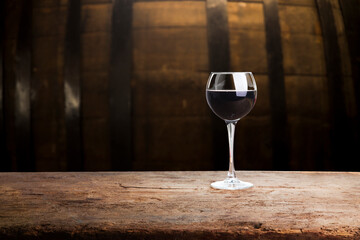 Pouring red wine into the glass against wooden background