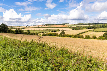 Fototapeta na wymiar An open, rolling Cotswold landscape of harvested fields in August near the hamlet of Hampen, Gloucestershire UK