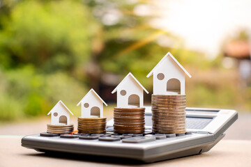 House model on a pile of coins and blurred natural green background. Real Estate Investment Ideas...