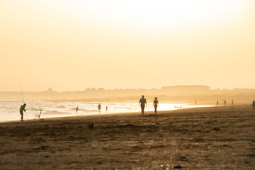 Fototapeta na wymiar sunset on the beach of huelva with silhouettes of people