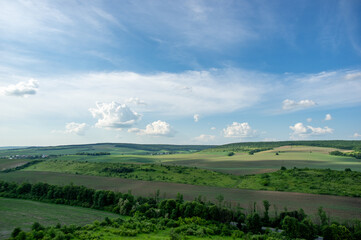 Fototapeta na wymiar Summer landscape and white clouds over green fields