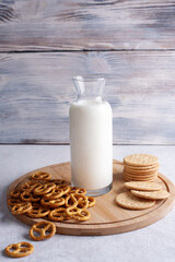 Cookies, mini salted pretzels and bottle with milk on white wooden background.