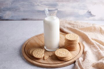 Breakfast, biscuit cookies and bottle of milk on white wooden background with textile.