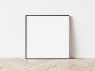 Empty square picture frame with thin dark border laying on wooden parquet floor, white wall in background. 3D illustration.