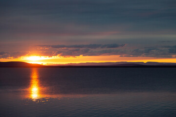 Beautiful red and yellow sunset over the lake. The sun sets directly into the water at sunset, background landscape photo