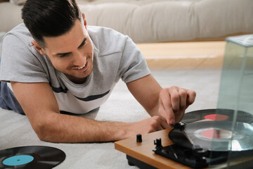 Happy man using turntable while lying on floor at home
