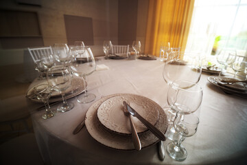 Table with wine glass, plates full serving. Napkins and cutlery. Low light. Selective focus. Ready to party, celebrate. Restaurant services, public catering enterprises. without food