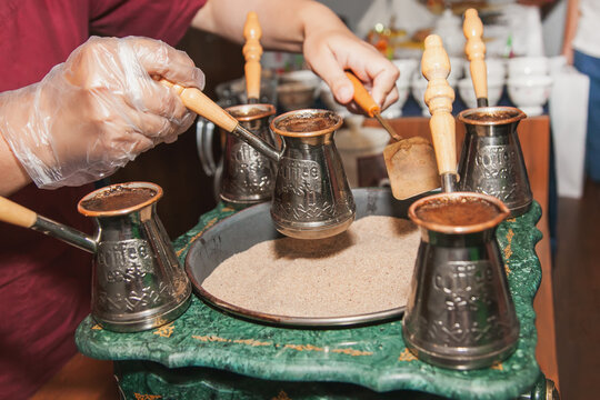 Woman makes turkish coffee on a coffee machine with sand in cezve. Oriental, east coffee