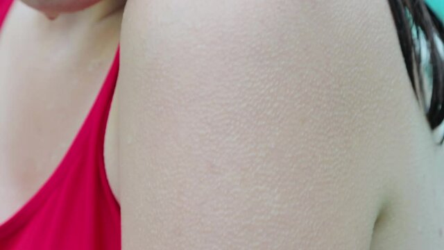 Close-up of a female hand covered with goose bumps. A wet woman in a red bathing suit is shivering from the cold.