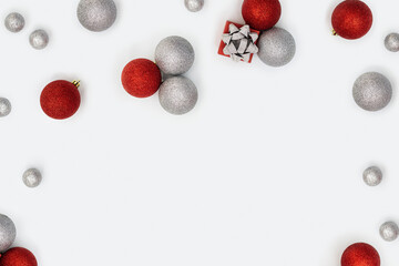 Merry Christmas and Happy New Year frame. Bright holiday flat lay with shiny red and silver Christmas balls and small gift box or present