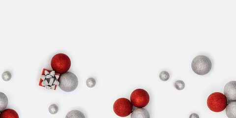 Christmas composition with silver and red christmas balls and gift box with surprise on white. New Year holiday banner