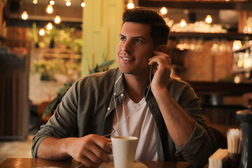 Man listening to audiobook at table in cafe