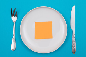 Colored Sticky Note or Memo Paper on White Ceramic Plate Lying On Blue Background - Top View, Flat Lay