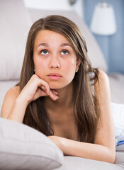 Female teenager is feeling distressed and lonely alone at home.
