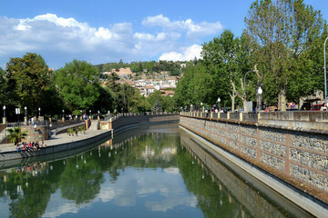Fototapeta premium River Genil from the Roman bridge in Granada with a lot of water flow in which trees and houses are reflected