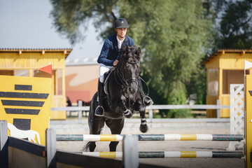 closeup portrait of black stallion horse and handsome man rider jumping obstacle