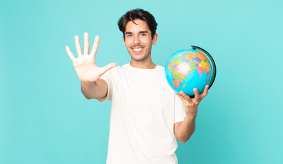 young hispanic man smiling and looking friendly, showing number five and holding a world globe map
