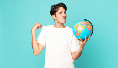 young hispanic man looking arrogant, successful, positive and proud and holding a world globe map