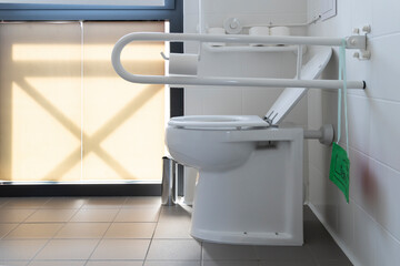 Bathroom equipped with toilet for the elderly and disabled people with fall prevention handle.