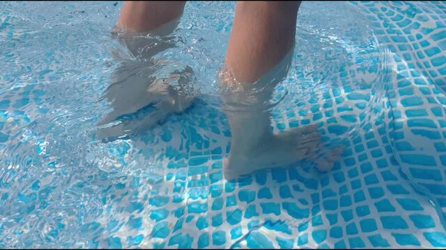 Young man walks barefoot on clear water in the pool